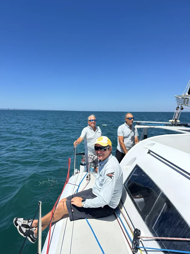 Crew relaxing momentarily on deck of Stealth catamaran Cut Snake between maneuvers