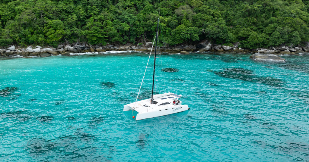 Stealth catamaran Haruki anchored in turquoise water near Ko Racha Thailand
