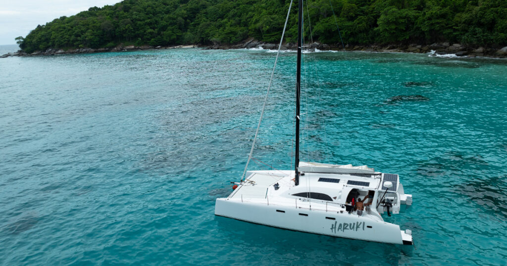 Close aerial view of Stealth performance catamaran Haruki at anchor near tropical island