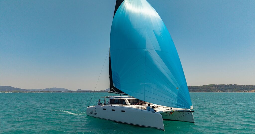 Stealth 13.2 performance catamaran sailing under large blue asymmetric spinnaker